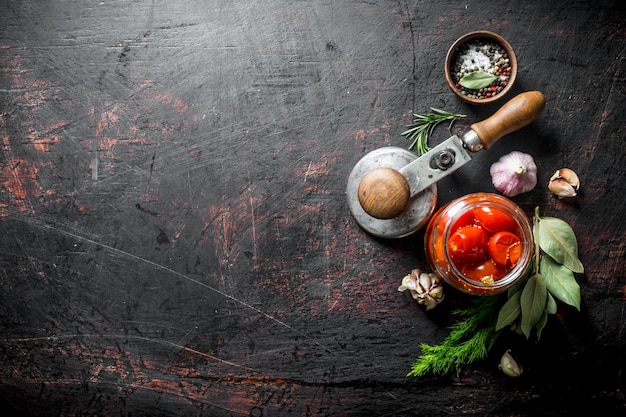 Ingemaakte tomaten in een glazen pot met knoflookkruiden en laurierblad