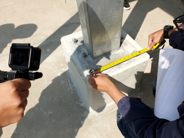 Ingenieur controleert de afstand van de verbindingsbouten van de grondplaat voor de staalconstructie van de zonne-carport