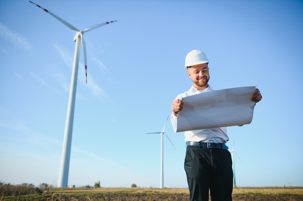 Ingenieur controleert energieproductie op windturbine. Arbeider in windmolenpark in helm.