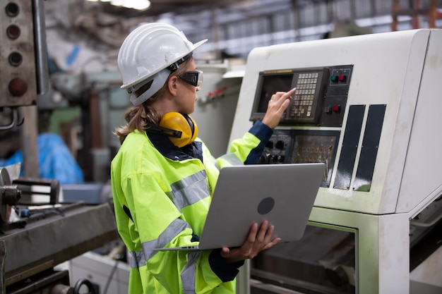 Foto ingenieur die een laptop gebruikt tijdens het bedienen van een machine in een fabriek