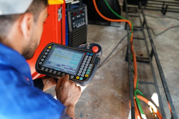 Ingenieur die het bedieningspaneel controleert en de nieuwe robotarm van Automatics en de bedieningsmachine in de fabriek leert