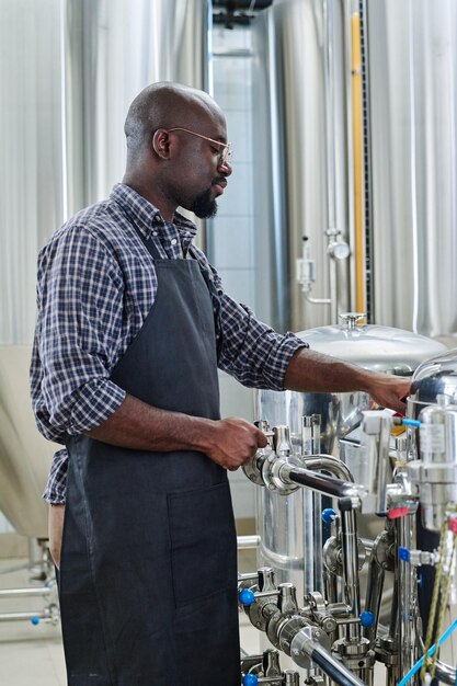 Ingenieur die het werk van apparatuur in brouwerijfabriek controleert