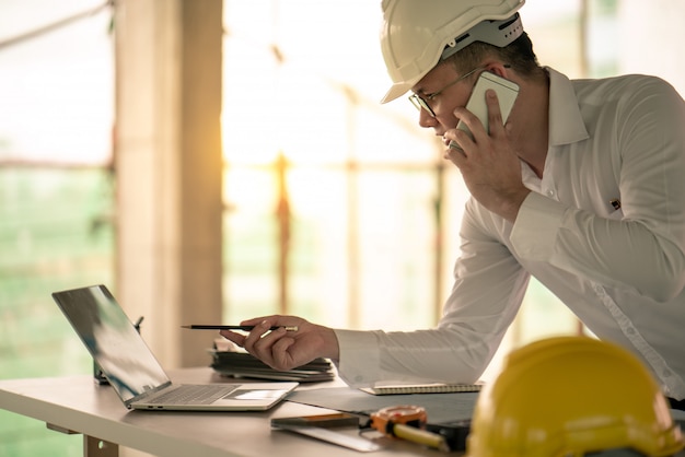 Foto ingenieur die met computerlaptop over bouwplan werkt aan plaats