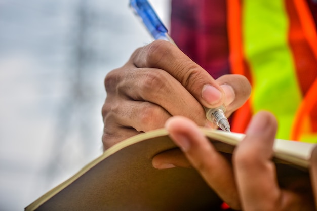 Ingenieur die op notitieboekje op het werk schrijft