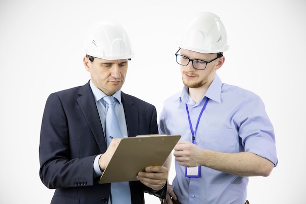 Ingenieur en architect in veiligheidshelmen bespreken project terwijl ze aantekeningen maken in het klembord