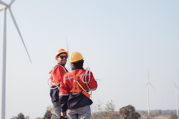 Ingenieur en technicus bespreken onderweg met windturbines op de achtergrond