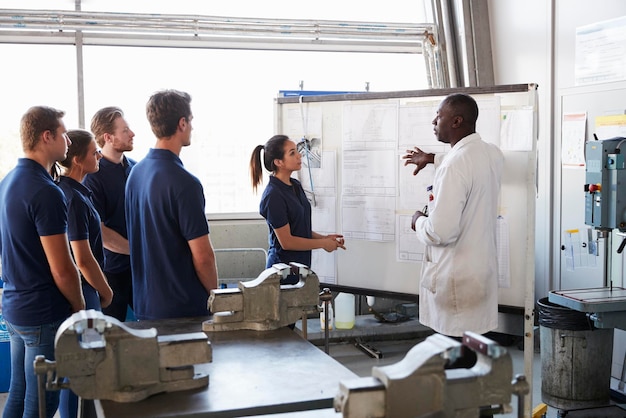 Ingenieur en vrouwelijke leerling presenteren op whiteboard