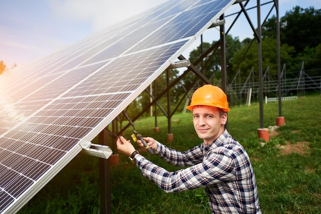 Ingenieur in helm verbindt zonnepanelen op een groene plantage Groene ecologische energieopwekking