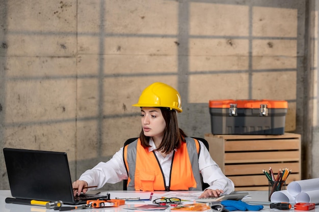 Foto ingenieur jonge schattige slimme brunette meisje civiele werknemer in helm en vest op computer