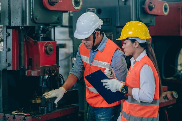 Ingenieur mannelijke training en check machine met vrouw werknemer team in metaalindustrie fabriek