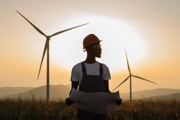 Ingenieur met blauwdrukken die zich onder windmolenlandbouwbedrijf bevinden