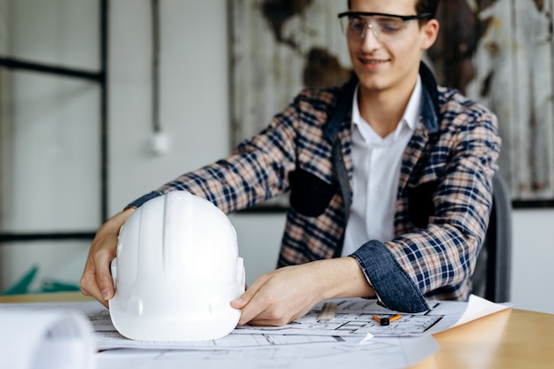 Ingenieur met bouwvakker in zijn handen die op kantoor werken