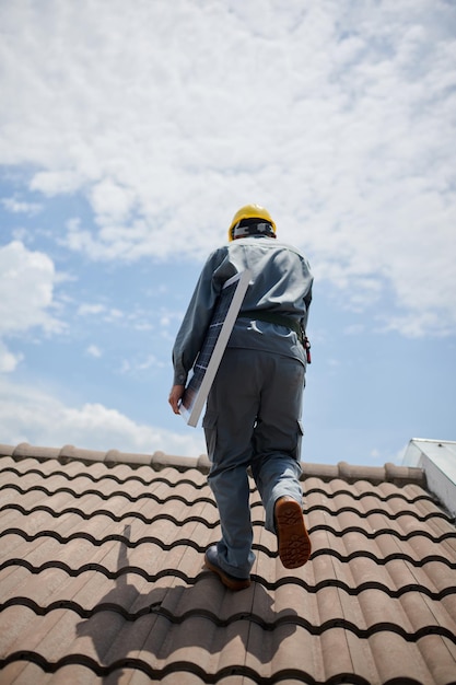 Ingenieur met zonnepaneel bij het lopen op het dak van achteren