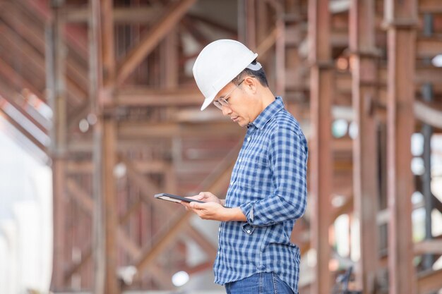 Ingenieur op het bouwterrein Man in hardhat met tablet op de bouwplaats van de infrastructuur