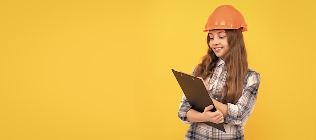 Ingenieur tiener meisje gelukkig tiener meisje in helm en geruit hemd maken van aantekeningen op Klembord notities maken Kind in harde hoed horizontale posterontwerp Banner koptekst kopie ruimte