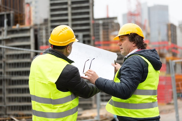 Ingenieurs bespreken de blauwdruk op de bouwplaats