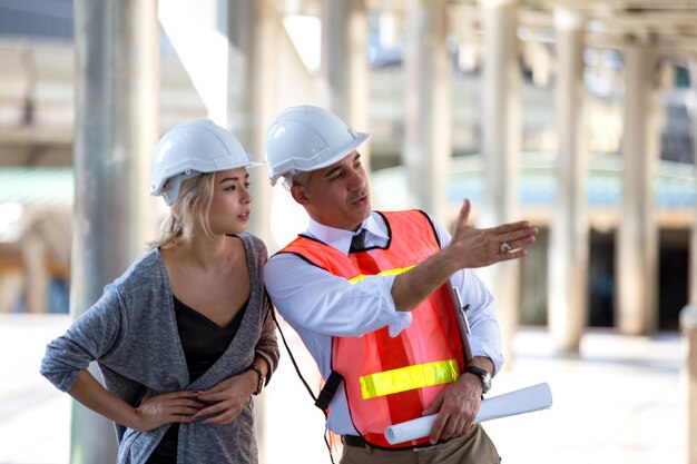 Foto ingenieurs bespreken de blauwdruk terwijl ze buiten staan