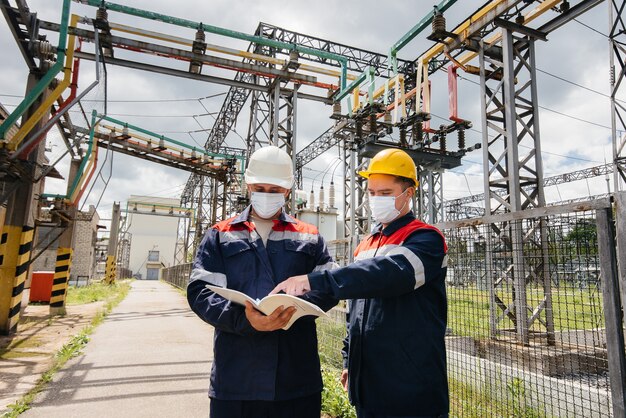 Ingenieurs elektrische onderstations voeren een onderzoek uit van moderne hoogspanningsapparatuur in het masker ten tijde van pandemie. energie. industrie.