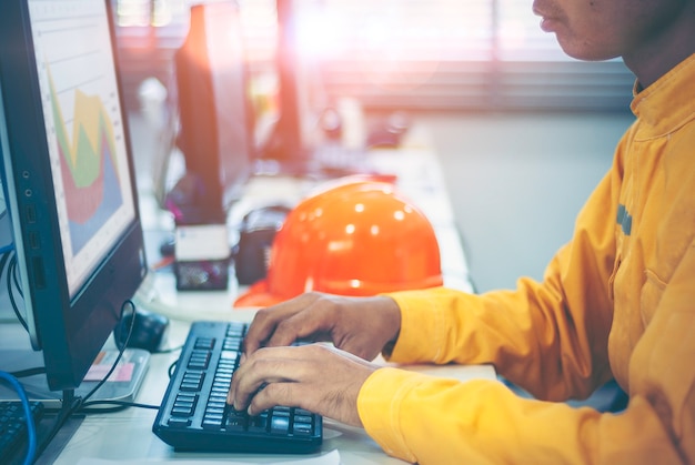 Foto ingenieurs, in oranje gehulde technici gebruiken een computer op kantoor