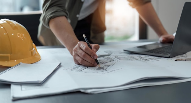 Foto ingenieurs man aan het werk op kantoor met blauwdrukken ingenieur inspecteert architectonisch plan dat een bouwproject schetst