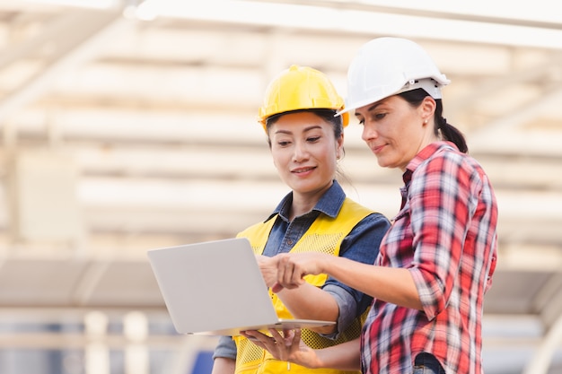 Ingenieurs twee vrouw die aan plan bouwconstructie werken met laptop in stad