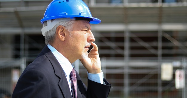 Ingenieursbouwer bij bouwwerf die op de telefoon spreken