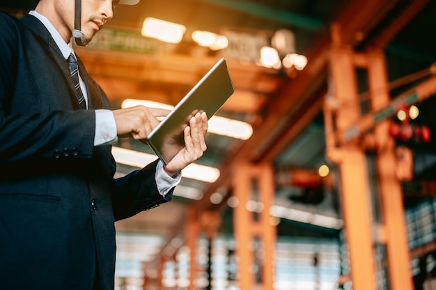 Ingenieursmanager controleert handleiding op tablet en beveelt werknemer om de robothand van de draaibank te gebruiken