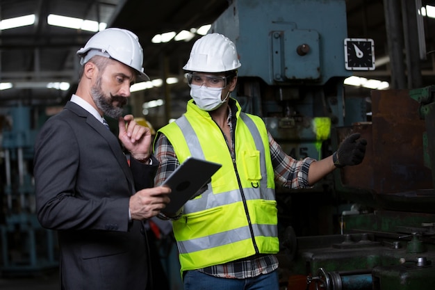 Ingenieursmanager en fabrieksarbeidersteam die machine in productielijn controleren. Teamwerkconcept.