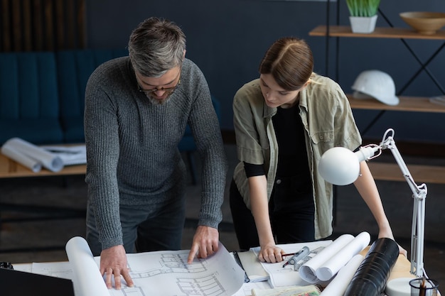 Ingenieursteam dat op kantoor werkt met blauwdrukken en architectenapparatuur, schetst, onderhandelt en een bouwproject plant. Partners bespreken op het werk. Bedrijfsbouwconcept.