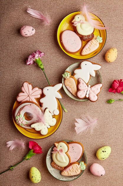 Ingerichte esthetische paaskoekjes roze bloemen met veren en eieren Lente pastel achtergrond