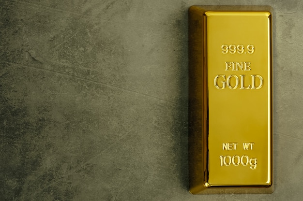 Ingot of pure gold metal bullion on a gray texture.