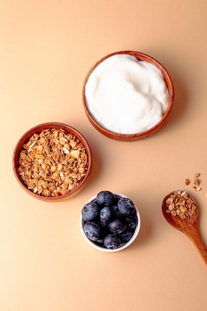 Ingredient for breakfast granola greek yogurt blueberry on beige background top view