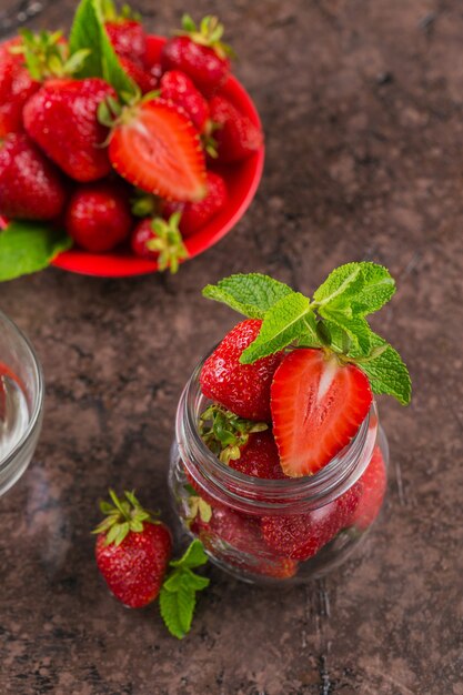 수제 딸기 잼 또는 잘 익은 달콤한 딸기와 민트 잎이 달린 유리 항아리에 마멀레이드 재료