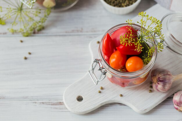 Ingrediente per sottaceti pomodori con aneto sul tavolo della cucina in stile rustico