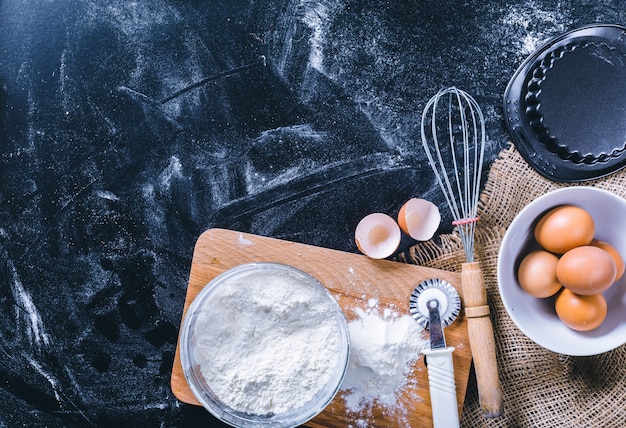 Ingrediënten en gebruiksvoorwerp voor het bakken op het zwarte bord, bovenaanzicht