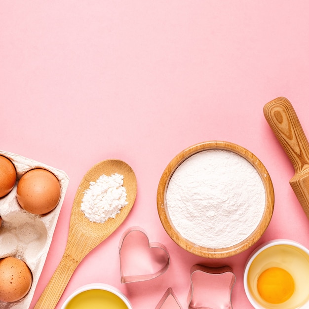 Ingrediënten en gebruiksvoorwerpen voor het bakken op een pastelkleurige achtergrond, bovenaanzicht.