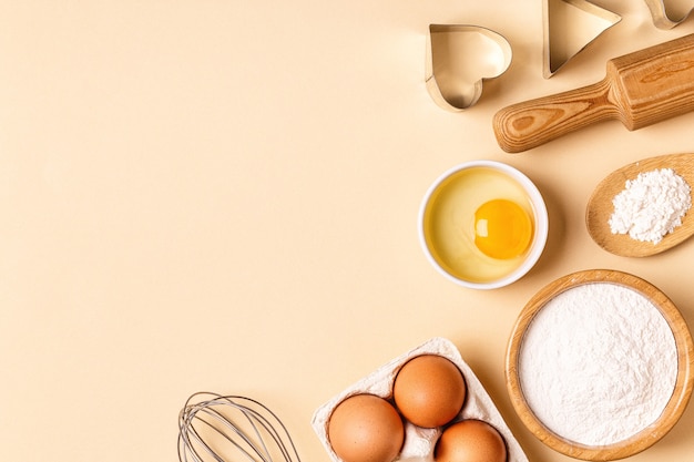 Ingrediënten en gebruiksvoorwerpen voor het bakken op een pastelkleurige achtergrond, bovenaanzicht.