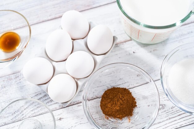 Ingrediënten in glazen mengkommen om wentelteefjes op een houten tafel te bereiden