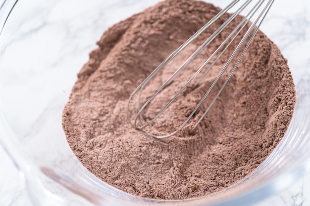 Ingrediënten mengen in een glazen mengkom om een chocolade cupcake te bakken.