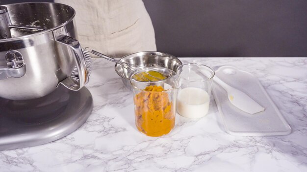 Ingrediënten mengen in elektrische keukenmixer om pompoenkruid cupcake te bakken.