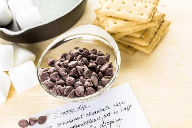 Ingrediënten smores dip bereid met grote marshmallows in gietijzeren pan.