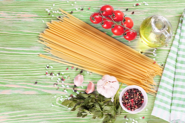 Ingrediënten van pasta en kruiden op groene houten ondergrond