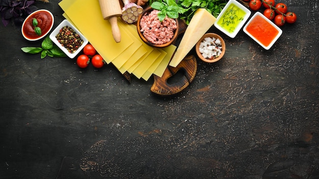 Ingrediënten voor de bereiding van Lasagne Tomatensaus pasta Op een zwarte achtergrond Bovenaanzicht Vrije ruimte voor uw tekst