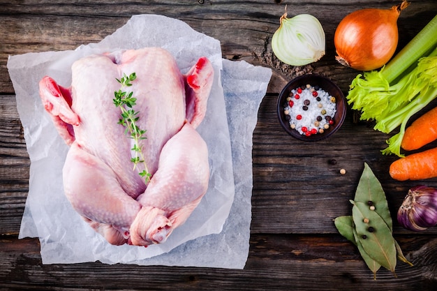 Ingrediënten voor de soepbouillon rauwe hele kip wortelen selderij uien op rustieke houten achtergrond