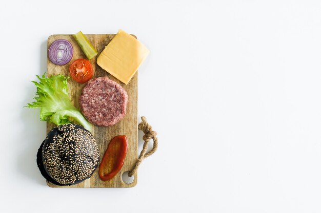 Ingrediënten voor de zwarte Hamburger op houten snijplank.