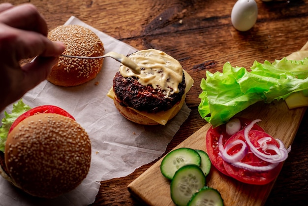 Ingrediënten voor hamburger cheeseburger Houten achtergrond De hamburger is besmeurd met saus Koken Hamburger dag