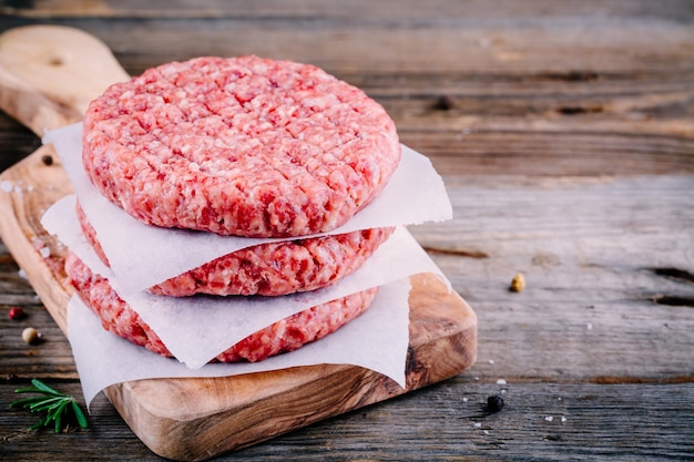 Ingrediënten voor hamburgers rauwe rundergehaktkoteletten op houten achtergrond