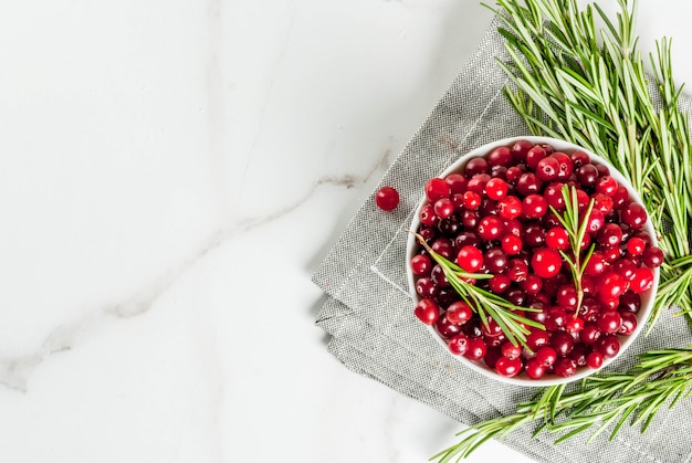 Ingrediënten voor herfst- en wintercocktails, een tak rozemarijn en een cranberry op een witte marmeren tafel, bovenaanzicht