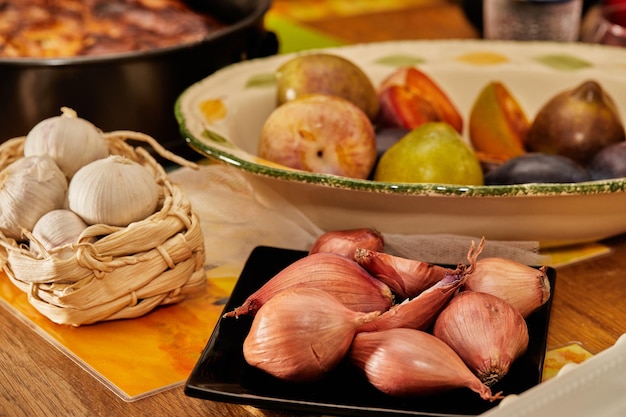 Ingrediënten voor het koken op tafel sjalotten paarse uien en pruimen van verschillende kleuren