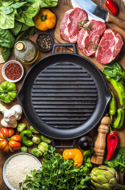 Ingrediënten voor het koken van gezond vleesdiner Rauw ongekookt rundvleeslapjes vlees met groenten, rijstkruiden, specerijen en wijnfles over rustieke houten achtergrond